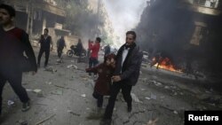FILE - People rush away from a site hit by what activists said were airstrikes by forces loyal to Syria's President Bashar al-Assad, in Douma, Syria, Nov. 7, 2015. Members of the State Department have expressed their belief that the U.S. should be directly targeting the Assad government with airstrikes.