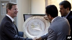 German Foreign Minister Guido Westerwelle (L) shakes hands with Libyan rebel National Transitional Council vice chairman and official spokesman Abdel Hafiz Ghoga after a news conference in Benghazi, Libya, June 13, 2011