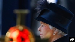 FILE - Britain's Queen Elizabeth II stands by a cross bearing a poppy during the service of remembrance at the Cenotaph in Whitehall, London, Nov. 11, 2012.
