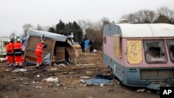 Workers dismantle migrants' dwellings in a makeshift camp near Calais, France, March 1, 2016. The slow tear-down of the encampment in Calais continued Tuesday, angering migrants who live there in squalid conditions in hopes of reaching a better life in Britian.
