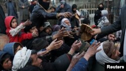 People reach out to receive bread in Kabul, Afghanistan, Jan. 31, 2022.