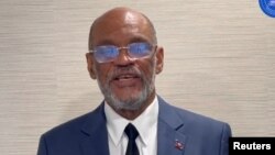 একটি হ্যান্ডআউট ভিডিও থেকে এক্স-এর মাধ্যমে প্রাপ্ত এই ছবিতে হাইতির প্রধানমন্ত্রী এরিয়েল হেনরি একটি অজ্ঞাত স্থান থেকে জাতির উদ্দেশ্যে ভাষণ দিচ্ছেন । (১১ মার্চ, ২০২৪)