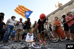 Anti-monarchy demonstrators burn pictures of the Spanish king during a protest against the visit of King Felipe VI of Spain to Catalonia, in Barcelona, June 15, 2021.
