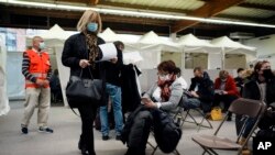 People wait during an observation period after having received Pfizer's COVID-19 vaccine at a vaccination site, in Fontainebleau, south of Paris, Dec. 3, 2021.