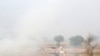FILE - A boy rides a bullock cart as smoke billows from paddy waste stubble as it burns in a field near Jewar, in the northern state of Uttar Pradesh, India, Nov. 6, 2018. 