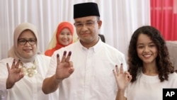 Gubernatorial candidate Anies Baswedan, center, and his family show their ink-dipped fingers after giving their votes during the local election in Jakarta, Indonesia, April 19, 2017.
