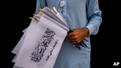 Seorang pedagang keliling menjual bendera Taliban di luar komplek kedutaan di Kabul, Afghanistan, pada 11 September 2021. (Foto: AP/Bernat Armangue)