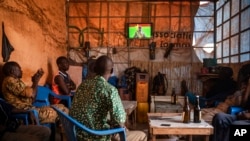 People gather in a bar to watch the presidential inauguration of junta leader Lt. Col. Paul Henri Sandaogo Damiba during his swearing-in ceremony broadcast on national television Feb. 16, 2022 in Ouagadougou, Burkina Faso.