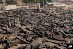 A man is backdropped by the yellow-blue 'Ukraine' road sign as he walks over broken pavement outside the crossing point from Ukrainian government to Russia-backed separatists-controlled territory in Stanytsia Luhanska, Luhansk region, Ukraine, Feb. 11, 2022.