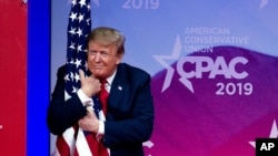 FILE - President Donald Trump hugs the American flag as he arrives to speak at Conservative Political Action Conference, CPAC 2019, in Oxon Hill, Md., March 2, 2019. 