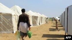 Seorang warga Yaman kembali menuju tenda pengungsian, yang dibangun dari dana sumbangan lembaga donor Kuwait, pada 1 Januari 2022. Kamp pengungsian tersebut terletak di sebelah timur laut Kota Ma'rib, Yaman. (Foto: AFP)
