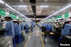 资料照：中国广东东莞一家生产移动游戏控制器的工厂工人在生产线上工作。（2021年12月7日）