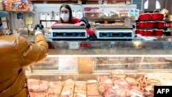 FILE - A customer pays for a cut of meat at Union Meat Company in Eastern Market in Washington, DC, on Feb. 8, 2022.