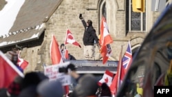 A person takes a photo as demonstrators against mandates related to Covid-19 vaccines and restrictions rally in downtown Toronto, Ontario, Canada, on Feb. 5, 2022.