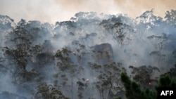 In this file photo, smoke and flames from a "back burn" are shown. The method aims to secure residential areas from encroaching bushfires, at the Spencer area in Central Coast, about 110 kilometers north of Sydney, Australia, on December 9, 2019. (Photo by SAEED KHAN /AFP)