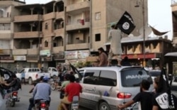 FILE - Members loyal to the Islamic State in Iraq and the Levant wave flags as they drive around Raqqa, June 29, 2014.