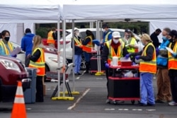 FILE - Wake County Health Department workers along with nurses and volunteers from area hospitals and emergency services are seen during a drive-through COVID-19 mass vaccination event at PNC arena in Raleigh, N.C., Feb. 11, 2021.