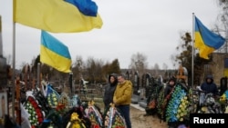 La gente visita las tumbas de sus familiares, miembros del servicio ucraniano muertos en combates contra las tropas rusas, cuando se cumple un año del ataque de Rusia a Ucrania, en un cementerio en la ciudad de Bucha, en las afueras de Kiev, Ucrania, el 24 de febrero de 2023.