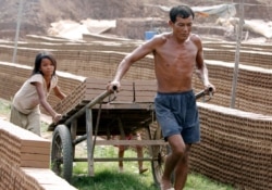 FILE - A Cambodian man and his daughter move a cart loaded with bricks at a brick factory in Chheuteal village, Kandal province, north of Phnom Penh, Cambodia, May 2, 2011.