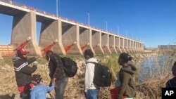 Un traficante mexicano lleva a una familia haitiana a través de la Presa Morelos sobre el río Colorado, el viernes 4 de febrero de 2022, desde Los Algodones, México, hacia Yuma, Arizona.