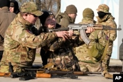 An instructor shows a woman how to use a Kalashnikov assault rifle, as members of a Ukrainian far-right group train, in Kyiv, Feb. 13, 2022.