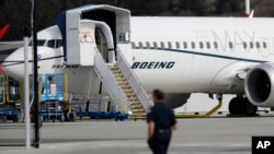 FILE - A worker walks next to a Boeing 737 MAX 8 airplane parked at Boeing Field in Seattle, March 14, 2019.. 