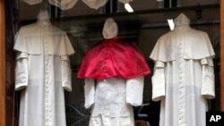 Tiga set pakaian dengan tiga ukuran dipajang oleh penjahit langganan Vatikan, siap dikirim untuk paus yang baru. (AP/Plinio Lepri)