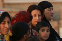 FILE - An Iraqi Kurdish woman from the Kakai minority looks on in her village located near the town of Kalak, east of Mosul, Oct. 26, 2016.