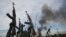 Rebel fighters hold up their rifles as they walk in front of a bushfire in a rebel controlled territory in Upper Nile State, South Sudan, Feb. 13, 2014. 