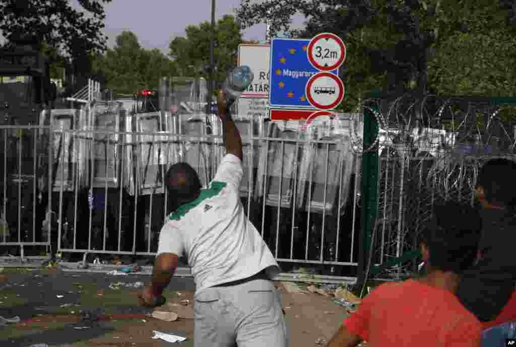 A migrant throws a bottle toward Hungarian police at the &quot;Horgos 2&quot; border crossing into Hungary, near Horgos, Serbia.