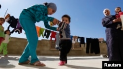A Syrian refugee girl helps her brother, who the family suspects has polio, to walk as their mother watches, in a mosque compound in the Shebaa area, southern Lebanon, Oct. 28, 2018.