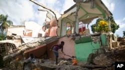 Luben Michel is helped by his wife Jeudi Remie to clear their house which was destroyed by the 7.2 magnitude earthquake six months ago in Marceline, Les Cayes, Haiti, Feb. 17, 2022.