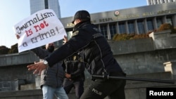 FILE - Police restrain a protester in front of the Parliament building in Baku, Azerbaijan, Dec. 28, 2021. At least eight journalists have been jailed in Azerbaijan since November in a move that press freedom groups characterize as politically motivated and retaliatory.