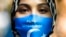 FILE - A woman wears a face mask reading 'Free Uyghurs' as she attends a protest during the visit of Chinese Foreign Minister Wang Yi in Berlin, Sept. 1, 2020. 