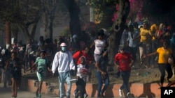 Factory workers run from tear gas fired by police trying to disperse their protest for salary increases in Port-au-Prince, Haiti, Feb. 23, 2022. 