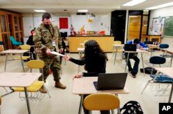 Guru pengganti dan spesialis Garda Nasional New Mexico Army Michael Stockwell mengambil tugas geologi dari Lilli Terrazas, 15, di Alamogordo High School. (Foto: AP)