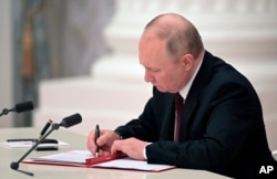 Russian President Vladimir Putin signs a document recognizing the independence of separatist regions in eastern Ukraine in the Kremlin in Moscow, Feb. 21, 2022.