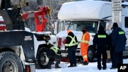 Police officers help a tow truck operator remove a mobile home from Nicholas Street, Feb. 18, 2022, in Ottawa, Canada.