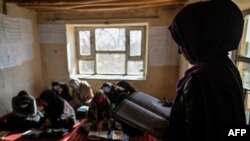 FILE - A teacher reading inside a class of grade 12 at a school in Langar village, in the Qarabagh district, some 56 km south-west of Ghazni, in Ghazni province, Nov. 14, 2021.