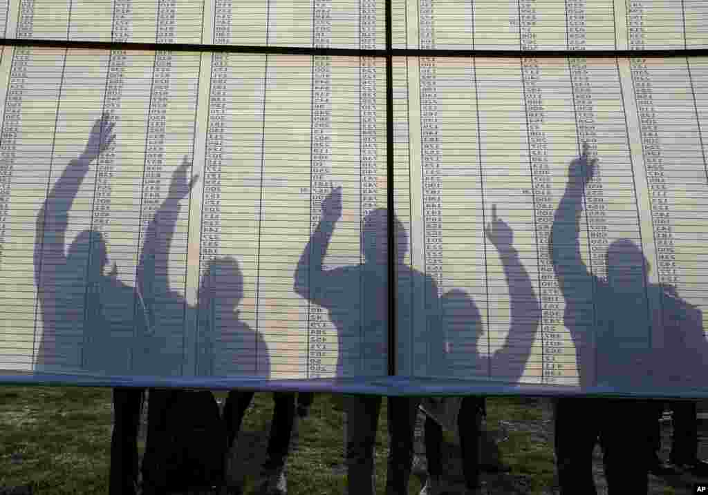 Election officials look up a duty chart that shows their allotted polling stations on the eve of the fourth phase of polling for Uttar Pradesh state elections in Lucknow, India.