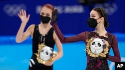 Gold medalist Anna Shcherbakova, right, waves as she walks with silver medalist and compatriot Alexandra Trusova after the women's free skate program at the 2022 Winter Olympics, Feb. 17, 2022, in Beijing.