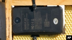 A GPS locater is attached to a frame on one of the beehives Helio Medina rents out in Woodland, Calif., Thursday, Feb. 17, 2022. (AP Photo/Rich Pedroncelli)