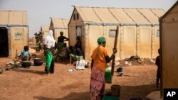 FILE - Displaced women prepare food at Kaya camp, some 100 kilometers north of Ouagadougou, Burkina Faso, Feb. 8, 2021. 