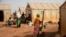 FILE - Displaced women prepare food at Kaya camp, some 100 kilometers north of Ouagadougou, Burkina Faso, Feb. 8, 2021. 