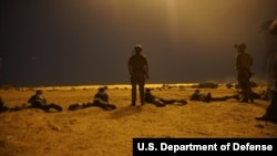 FILE - U.S. Army Special Forces soldiers observe as Nigerien armed forces service members fire their weapons with the assistance of Illumination rounds during Exercise Flintlock 2017 in Diffa, Niger, March 9, 2017. Flintlock is a Special Operations Forces exercise geared toward building interoperability between African and western partner nations.