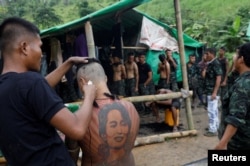 FILE - A young man sporting a tatoo of deposed Myanmar leader Aung San Suu Kyi gets a military-style haircut at a People's Defense Force training camp in an area controlled by ethnic Karenni rebels, Kayah state, Myanmar, Sept. 11, 2021.