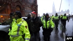Police officers escort an arrested protester to a police car during a protest over pandemic health rules and the Trudeau government in Ottawa, Canada, on Feb. 17, 2022.