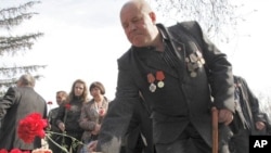 A veteran "liquidator" at the Chernobyl nuclear reactor places flowers during a ceremony to honor victims of the Chernobyl disaster, in Krasnoyarsk, April 26, 2011
