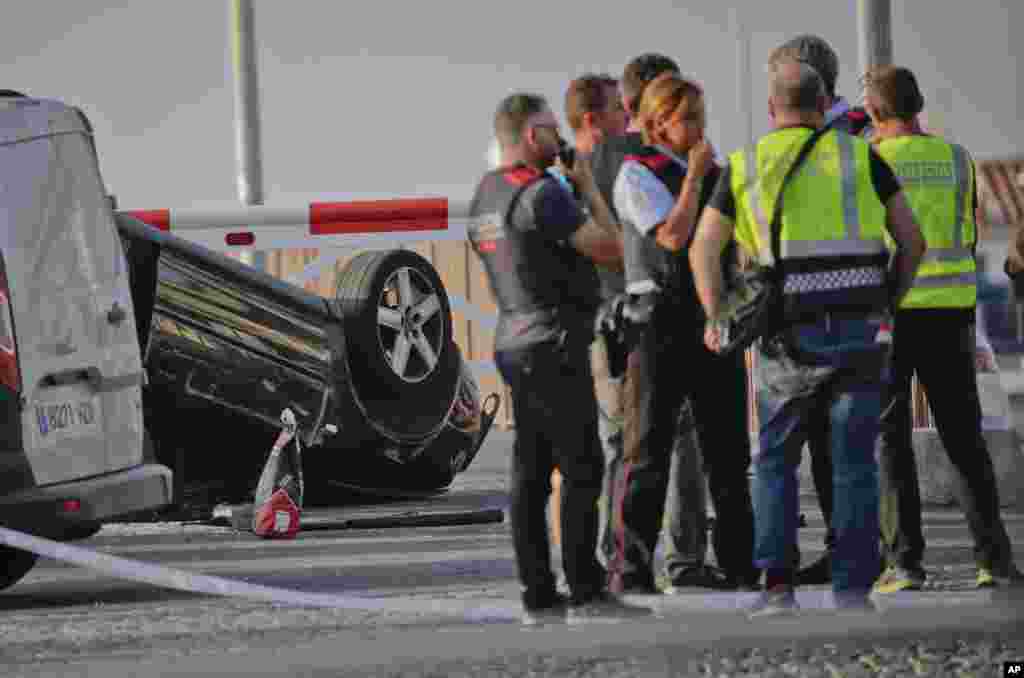 Police officers speak near an overturned car at the spot where terrorists were intercepted by police in Cambrils, Spain, Aug. 18, 2017.&nbsp;