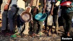 Ethiopian refugees who fled Tigray region, queue to receive food aid within the Um-Rakoba camp in Al-Qadarif state, on the border, in Sudan, December 11, 2020.